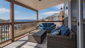 Ein überdachter Balkon mit Korbmöbeln, Deckenventilator und Meerblick.