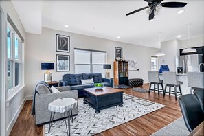 Un salon moderne comprenant un canapé, une table basse et un coin repas avec des chaises.
