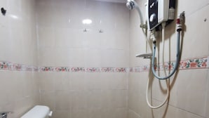 A small bathroom with a toilet, sink, and shower unit.