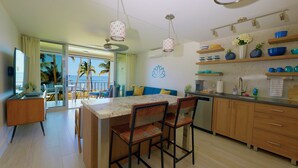 Una cocina moderna con una isla central, taburetes de bar y vistas al océano a través de amplios ventanales.