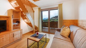 A wooden staircase, a sofa, a TV, and a balcony with a view.