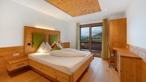 A wooden bedroom with a bed, nightstand, and a desk.