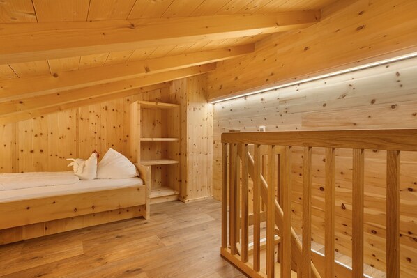 Une cabane en bois avec un lit en mezzanine, un escalier en bois et une petite table.