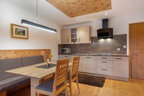 A modern kitchen with wooden cabinets, a built-in microwave, and a stove. - Thalerhof Apartment Katrin with Wi-Fi, Balcony & Garden (Vöran)