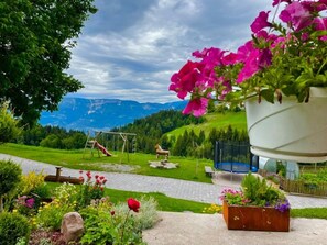 A garden with a swing set, a trampoline, and a view of mountains. - Thalerhof Apartment Katrin with Wi-Fi, Balcony & Garden (Vöran)