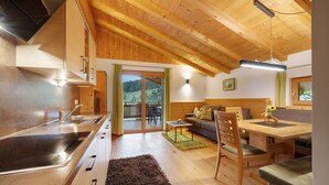 Een moderne keuken met een ingebouwde kookplaat, een eethoek met een houten tafel en stoelen, en een bank.