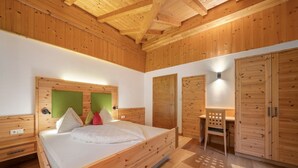 Een kamer met houten lambrisering, een bed, een bureau en een garderobe.