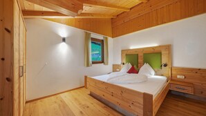 Ein Schlafzimmer mit Holzwänden, einem Bett, einem Nachttisch und einem Fenster mit Vorhängen.