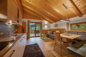 Una cocina moderna con armarios de madera, un comedor con mesa y bancos, y vistas a un balcón.