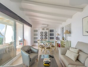 Een moderne woonkamer met een bank, fauteuil, eettafel en stoelen. Er is een balkon met uitzicht.