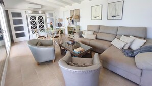 Un salon spacieux comprenant un canapé, des fauteuils, une table basse et un coin repas avec des chaises et une table.
