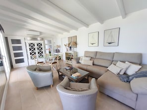 A spacious living room with a sofa, armchairs, a coffee table, and a dining area with chairs and a table.