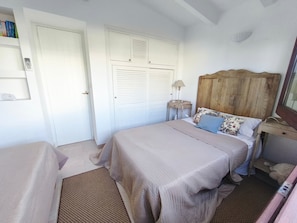 A bedroom with a bed, bedside table, lamp, and wardrobe.