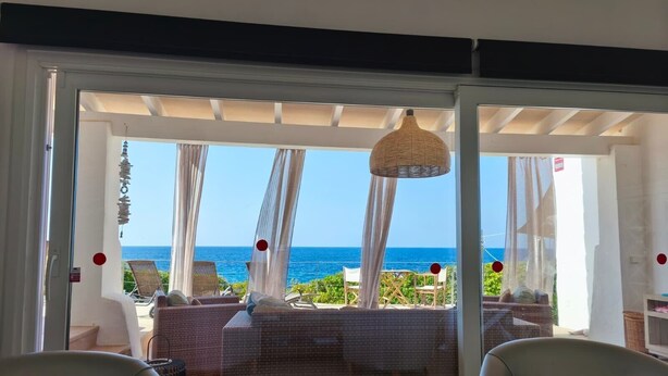 Une pièce avec vue sur la mer, un canapé en osier et un luminaire suspendu.