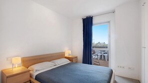 A bedroom with a bed, bedside tables, a window with curtains, and a view of the outside.
