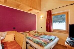 Un dormitorio con cama, televisión y ventana con vista a árboles.
