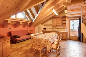 Ein gemütliches Dachzimmer mit Esstisch, Stühlen, einer Couch und einer Küchenzeile.