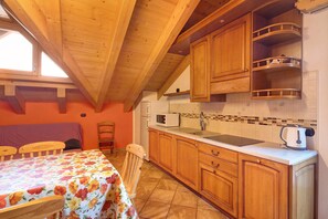 A kitchen with wooden cabinets, a countertop, a sink, and a kettle.