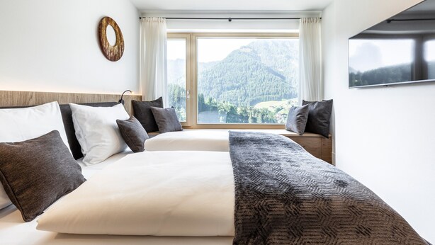 Una habitación de hotel con una cama grande, vistas a montañas y un televisor de pantalla plana.