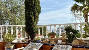 Una terraza con sillones de descanso, plantas en macetas y vistas del horizonte de la ciudad.