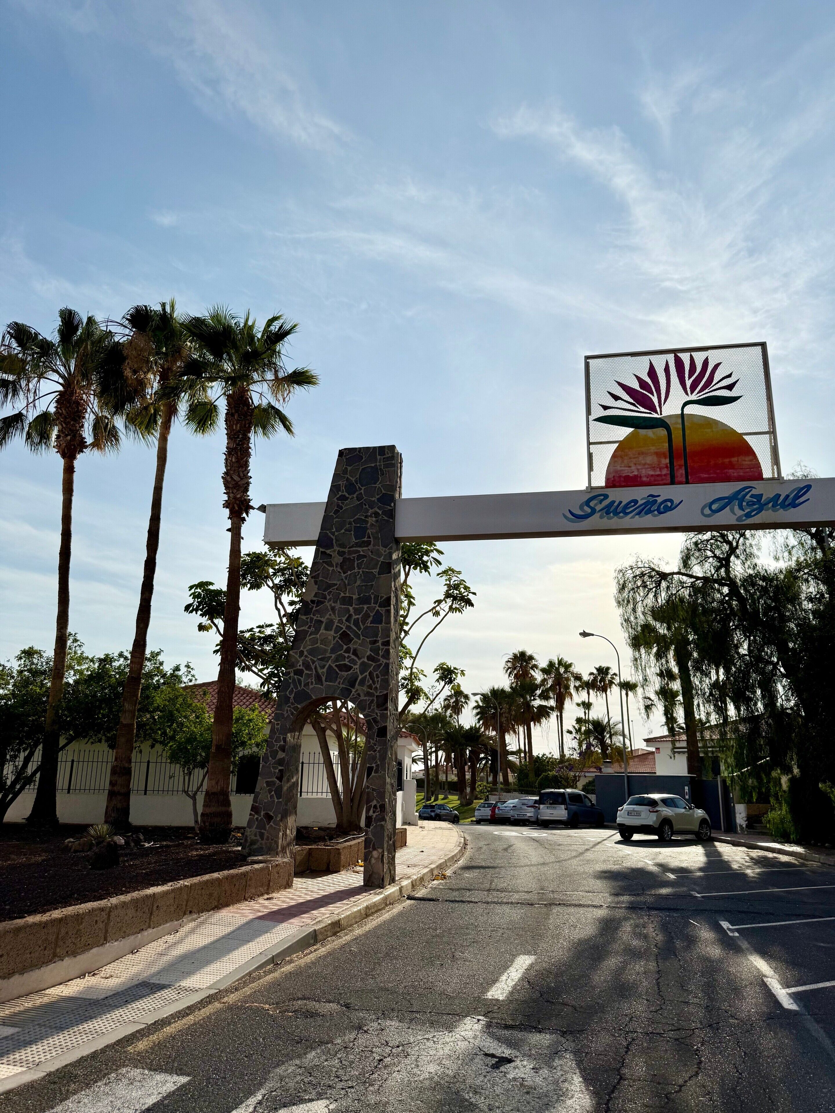 Un panneau de signalisation représentant des palmiers et un ciel dégagé.