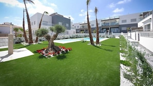 Un bâtiment moderne doté d’une piscine, d’une pelouse verdoyante et de palmiers.