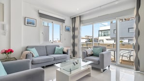 Un salon moderne avec un canapé, un fauteuil et une table basse en verre.