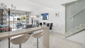 Une cuisine moderne dotée d’un îlot central, de tabourets de bar et d’un coin repas avec des chaises et une table.