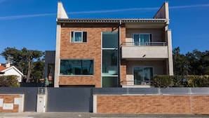 Un edificio moderno de dos pisos con fachada de ladrillo, ventanas grandes y un balcón.