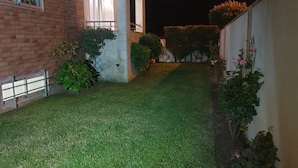 Un patio bien cuidado con césped, un edificio de ladrillo y una pared blanca.