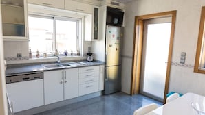 Una cocina equipada con lavavajillas, refrigerador, fregadero y ventana.