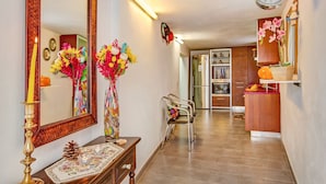 A hallway with a mirror, a clock, a vase with flowers, a table with a candle, and a chair. - Holiday Home "Casa del Callejón" with Mountain View, Terrace & Outdoor Shower (Tejeda)