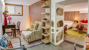 A compact room with a bed, a small table, a chair, a sofa, and a decorative wall with shelves. - Holiday Home "Casa del Callejón" with Mountain View, Terrace & Outdoor Shower (Tejeda)