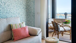 Un balcon agrémenté de meubles en osier, un canapé avec des coussins à rayures et un mur orné de motifs.