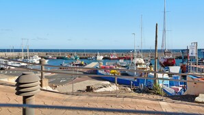 Un port de plaisance avec des bateaux amarrés, un ciel dégagé et une promenade pavée.