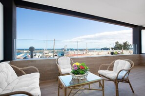 Un balcon agrémenté de meubles en osier, d’une table en verre et d’une plante en pot.