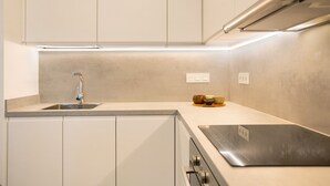 Une cuisine moderne dotée d’un évier en acier inoxydable, d’un four encastré et d’un plan de travail élégant.