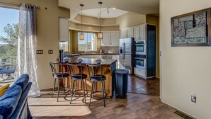 A modern kitchen with a central island, bar stools, and a large refrigerator. - Sedona Blue Jay Close Access To Numerous Trails, Hot Tub, Patio, Walkable (Sedona)