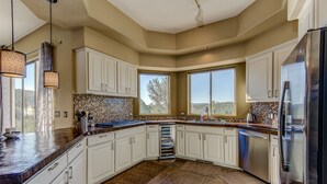 A spacious kitchen with white cabinets, a large island, and a view of the outdoors. - Sedona Blue Jay Close Access To Numerous Trails, Hot Tub, Patio, Walkable (Sedona)