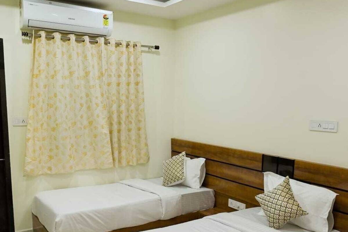 Una habitación con dos camas individuales, ventilador de techo, aire acondicionado y cortina.