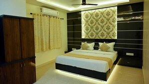 A modern bedroom with a bed, a wardrobe, a ceiling fan, and a decorative wall panel. - Hotel Golden Bliss (Bhopal)