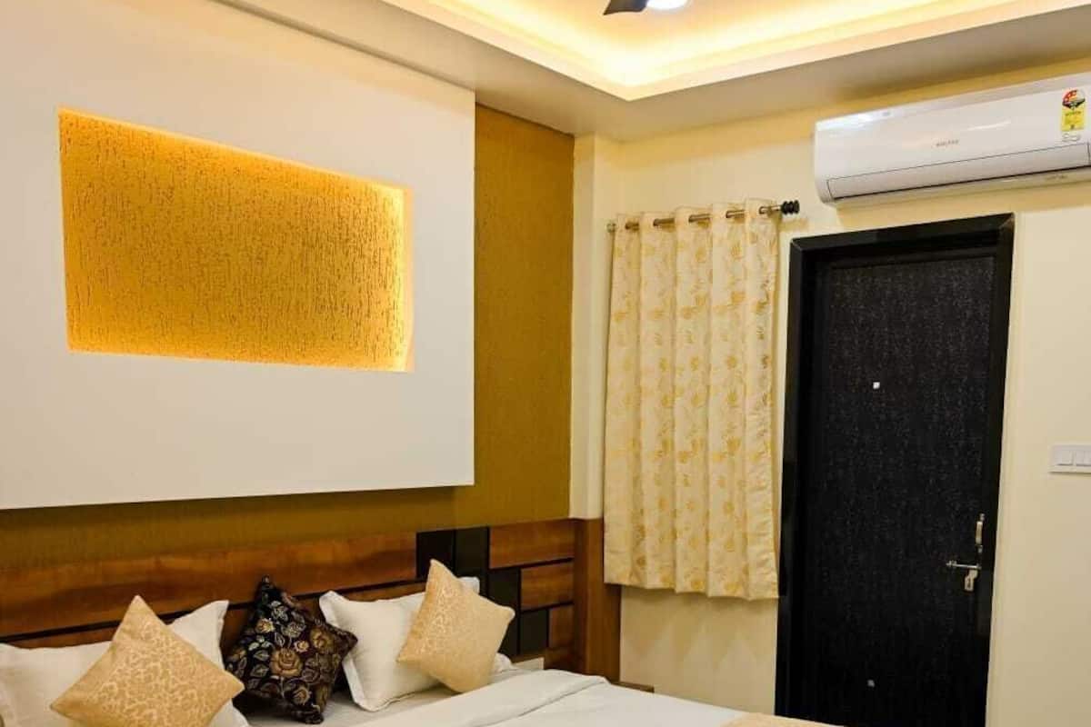 Habitación de hotel con cama, ventilador de techo, aire acondicionado de pared y puerta.