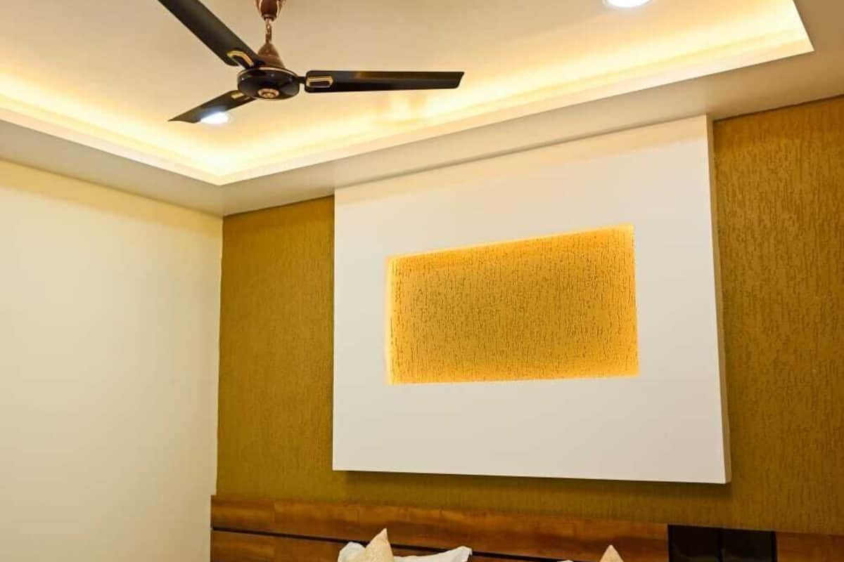 Una habitación de hotel moderna con una cama, ventilador de techo, iluminación empotrada y un cuadro abstracto grande en la pared.