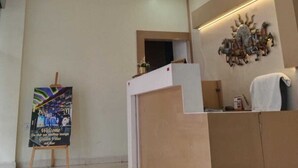 A hotel reception area with a chandelier, a welcome sign, and a decorative wall piece. - Hotel Golden Bliss (Bhopal)