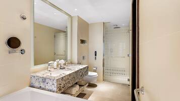 Un baño moderno con un espejo grande, un lavabo de mármol, un inodoro y una zona de ducha.
