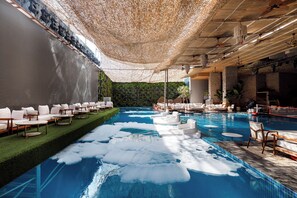 A pool area with artificial ice, lounge chairs, and a ceiling with hanging lights.