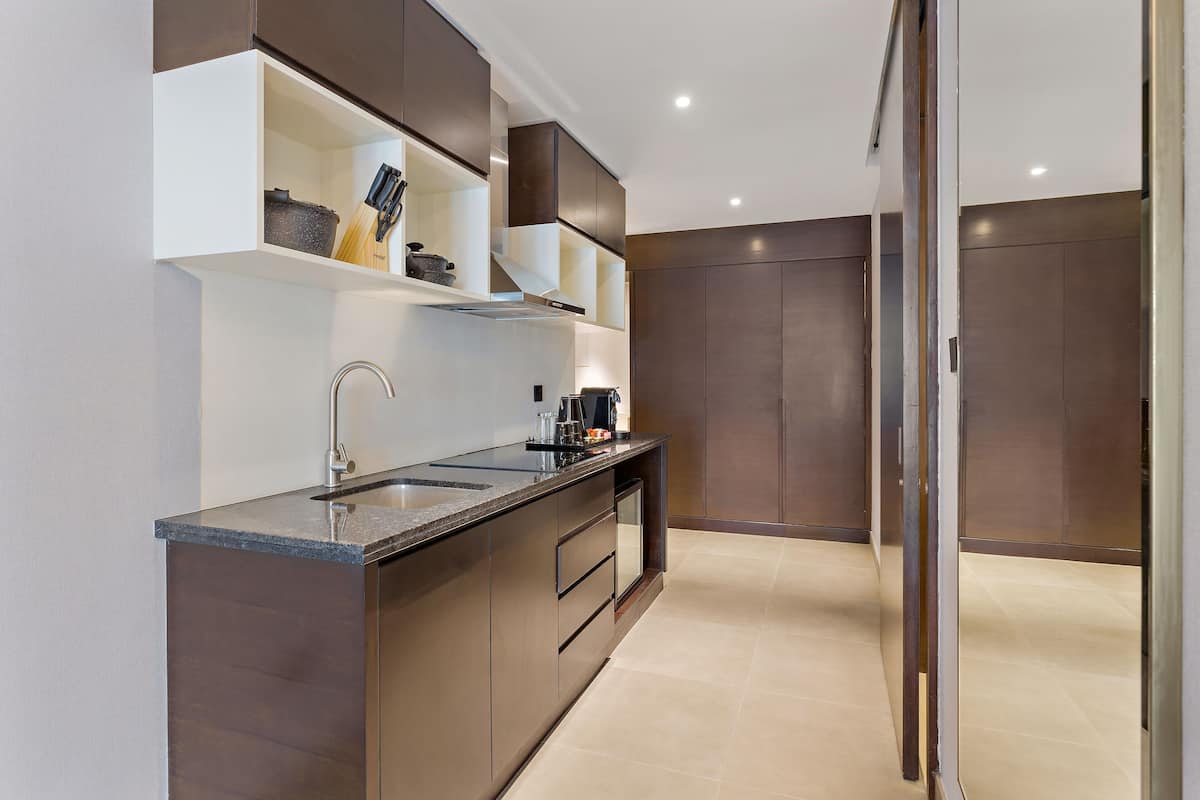A modern kitchen with dark cabinetry, a granite countertop, and stainless steel appliances.