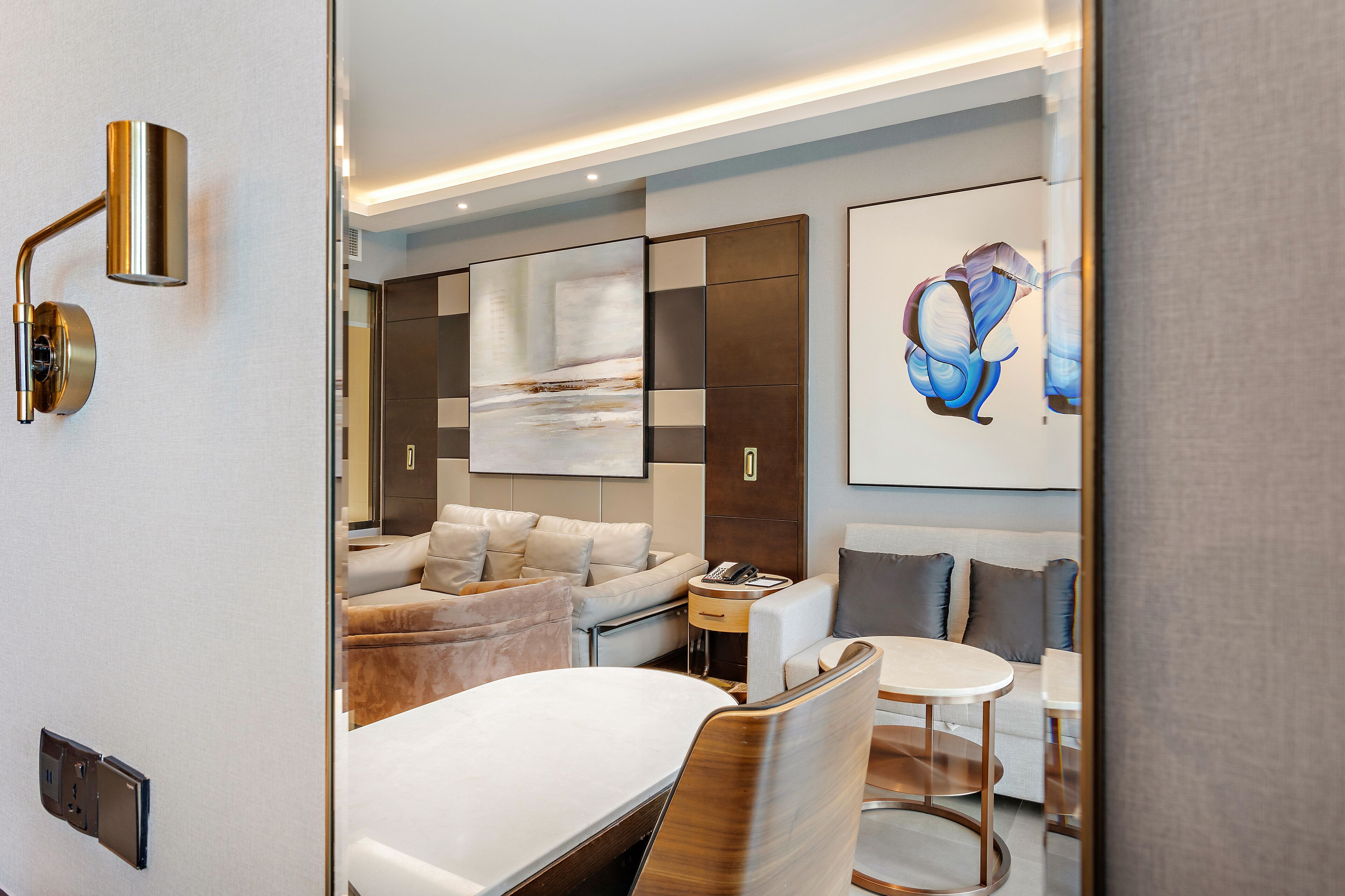 Une chambre d’hôtel moderne équipée d’un lit, d’un canapé, d’une table à manger et d’un grand tableau abstrait.