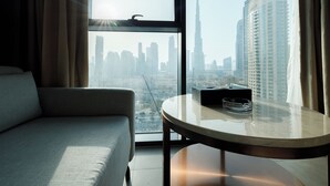 Une chambre d’hôtel avec vue sur les toits de la ville, une table ronde avec un cendrier en verre et un canapé.