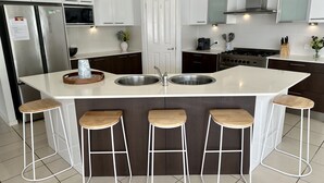 A modern kitchen with a central island, stainless steel appliances, and bar stools.